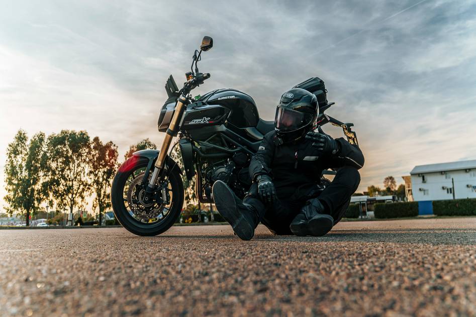 Motorcycle rider on an open road with scenic mountains in the background