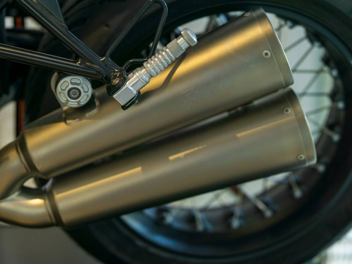 Traveler applying portable heat shield for motorcycle in foreign country garage
